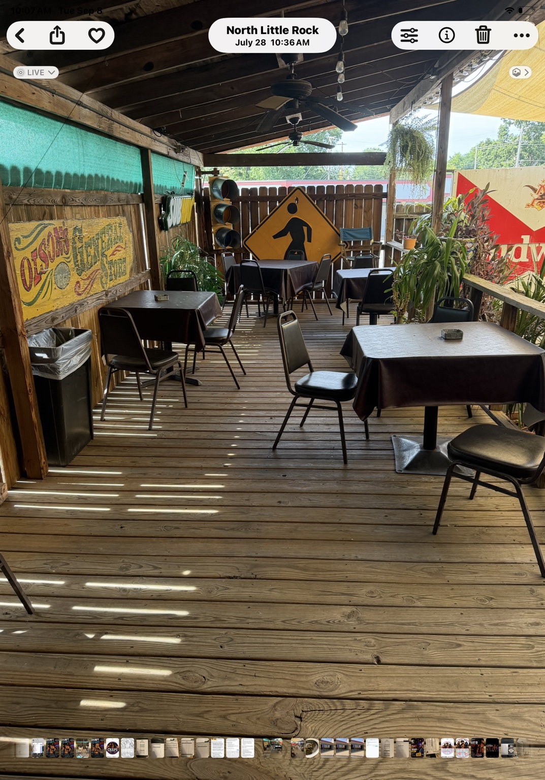 Covered wooden patio at CHAPS with tables, ceiling fans, plants, and vintage signs